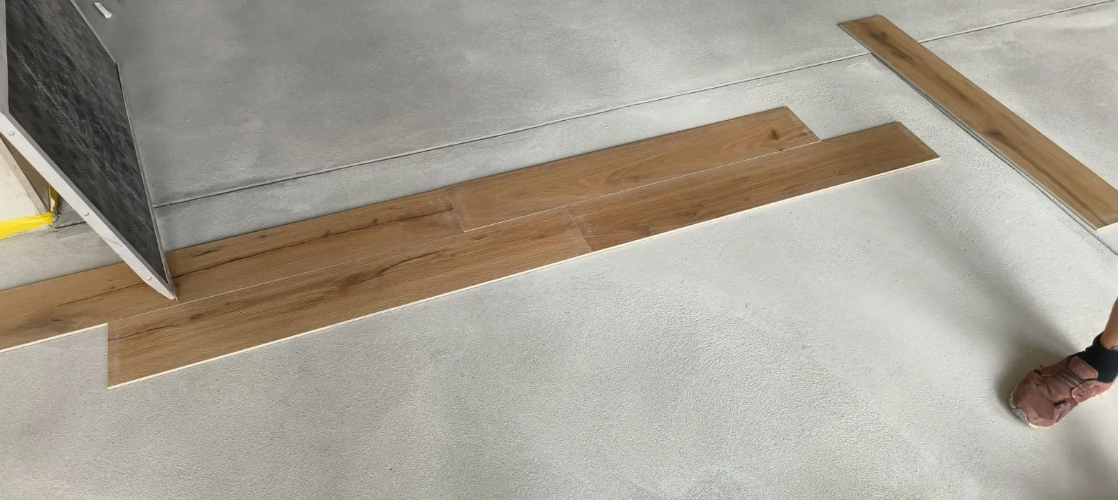 Oak wood floor planks laid out across the concrete floor for a trial run