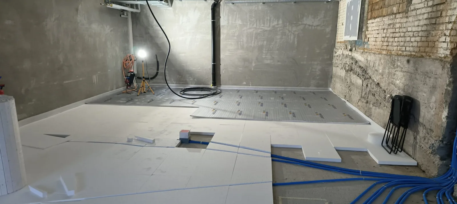 Sub-floor insulation panels and blue underfloor heating loops being installed