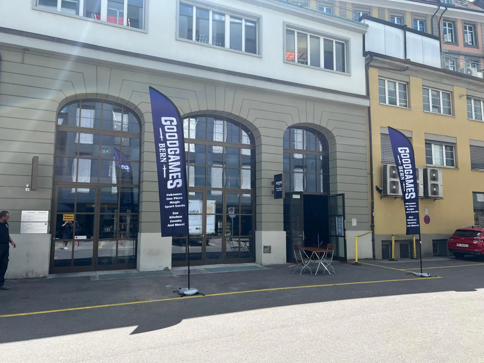 The GoodGames Bern entrance with arched windows and two branded flags out front