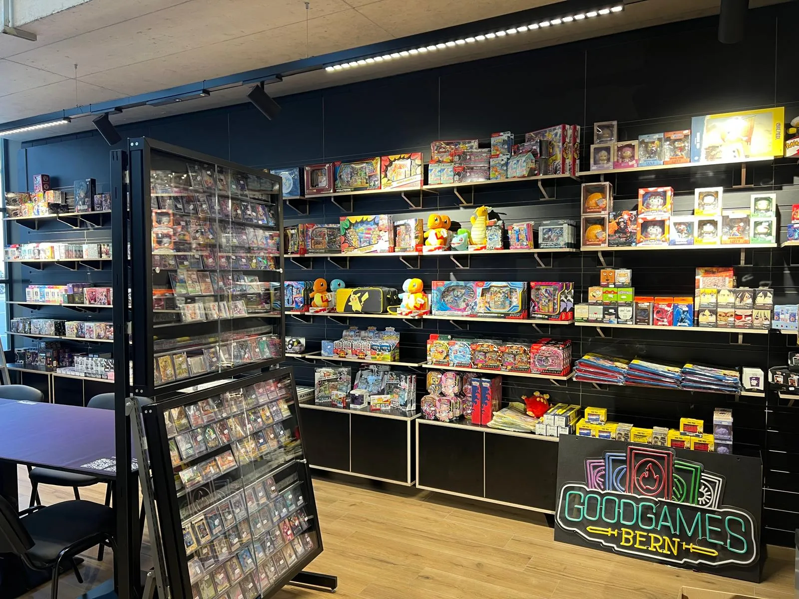 Shelf wall with board games, plushies, accessories and a neon GoodGames Bern sign