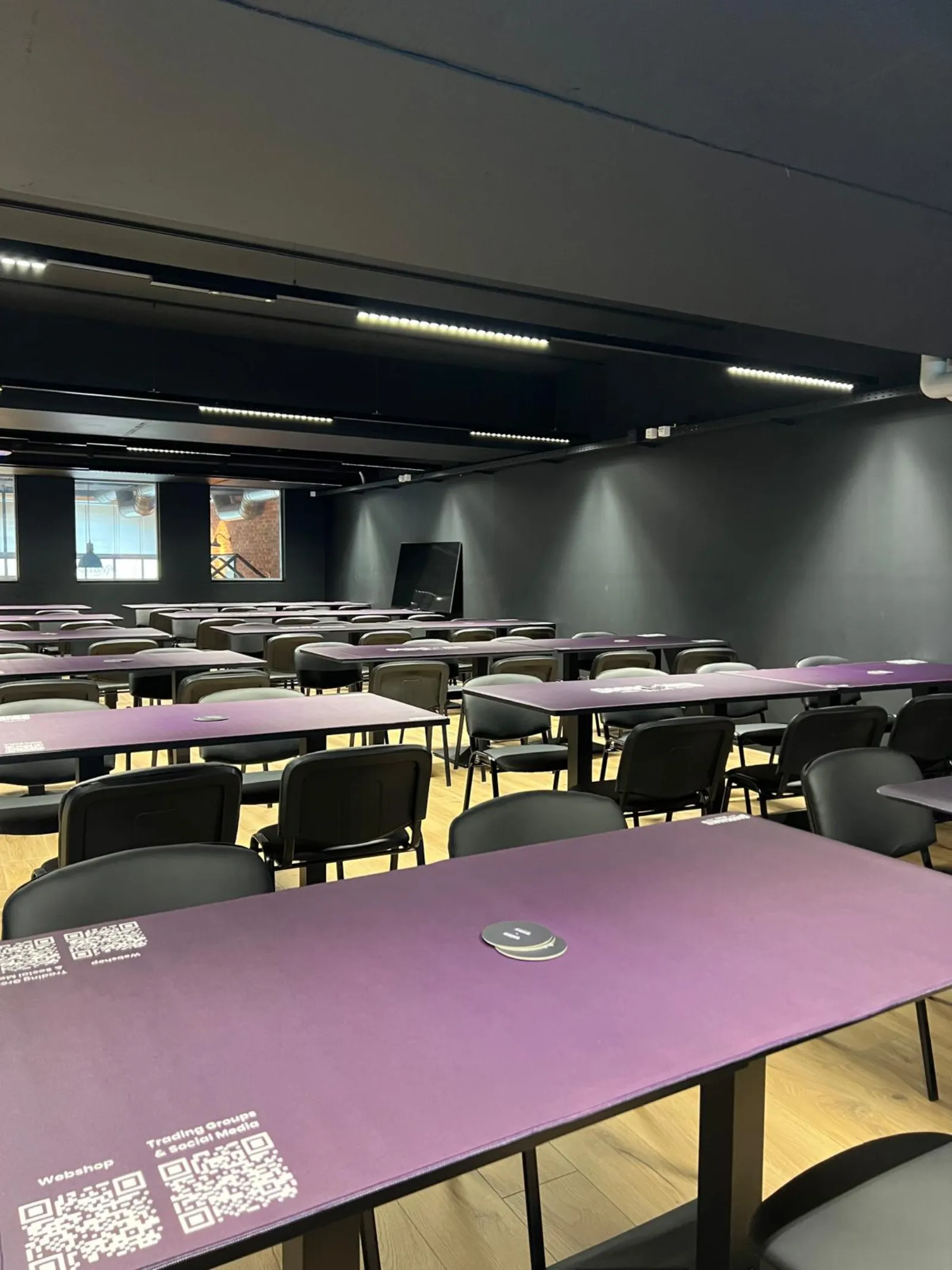 The empty tournament hall seen from the back, tables set with QR-code playmats