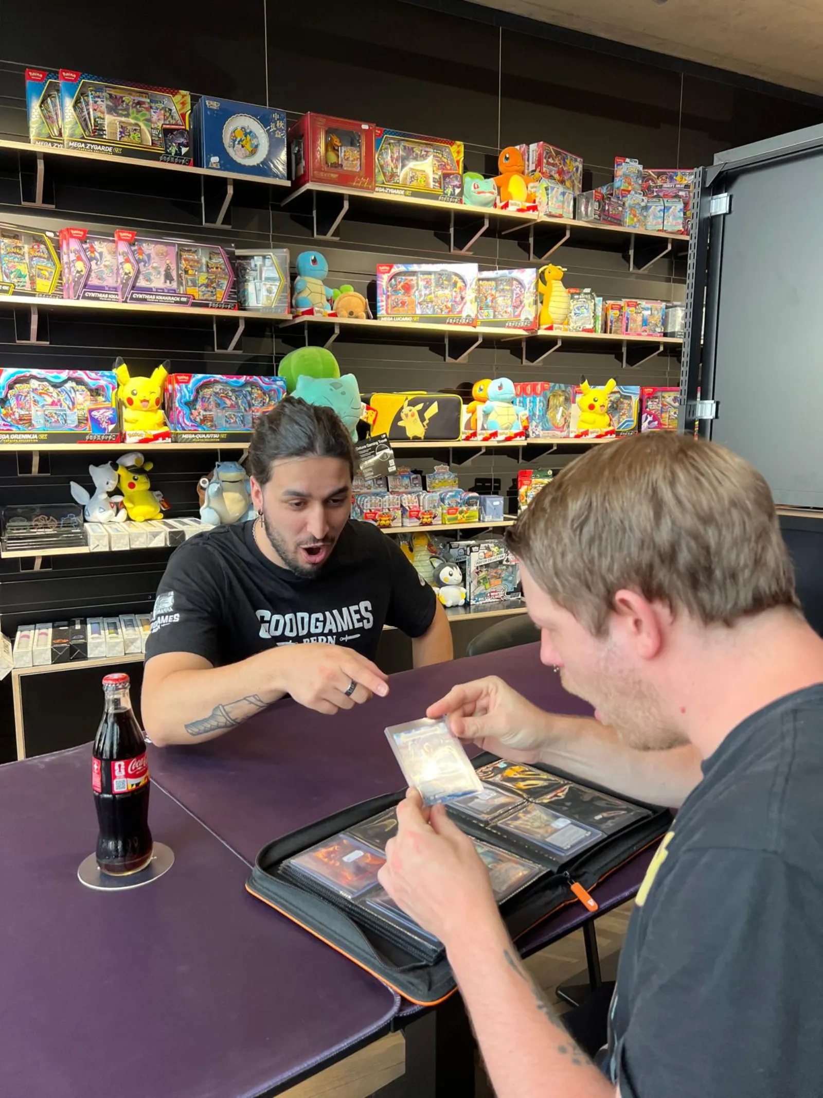 Two players trading cards over a binder at a play table