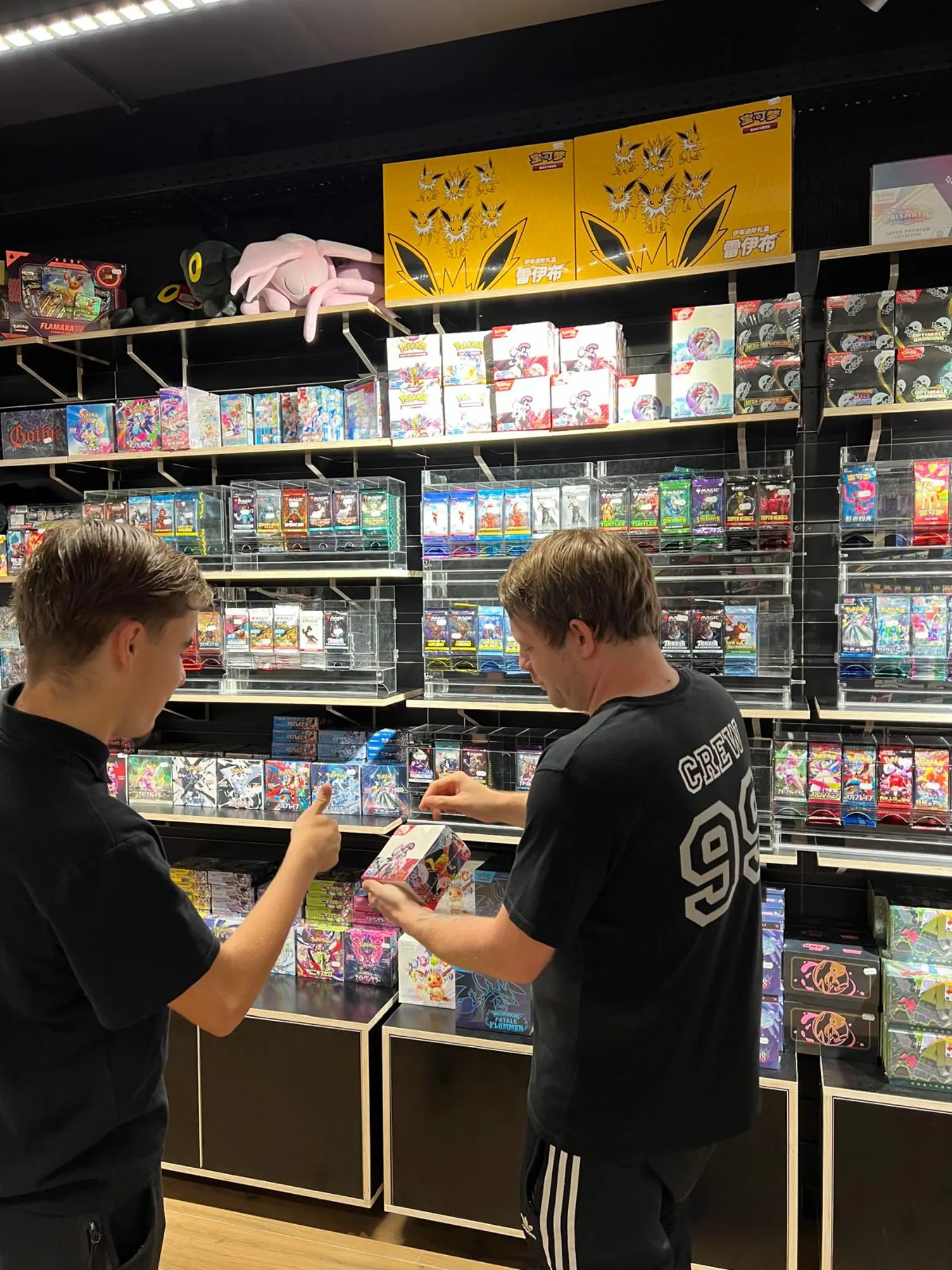 Two customers looking at a booster box in front of the card shelves